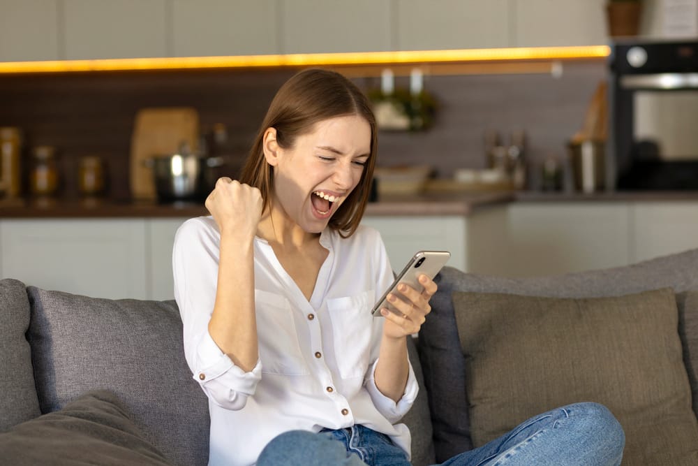Depositphotos_472174254_S Woman looking very happy with the results from her mobile