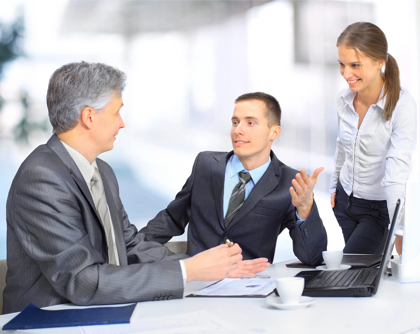 the onsite assistance Zwei Männer die ein Meeting miteinander haben und eine weibliche Sprachcoach beobachtet es